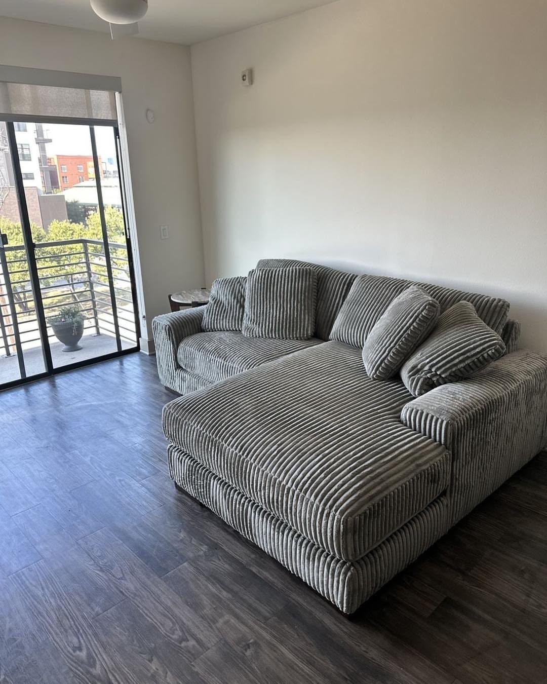 Grey corduroy sectional sofa with chaise in a living room with dark floors.