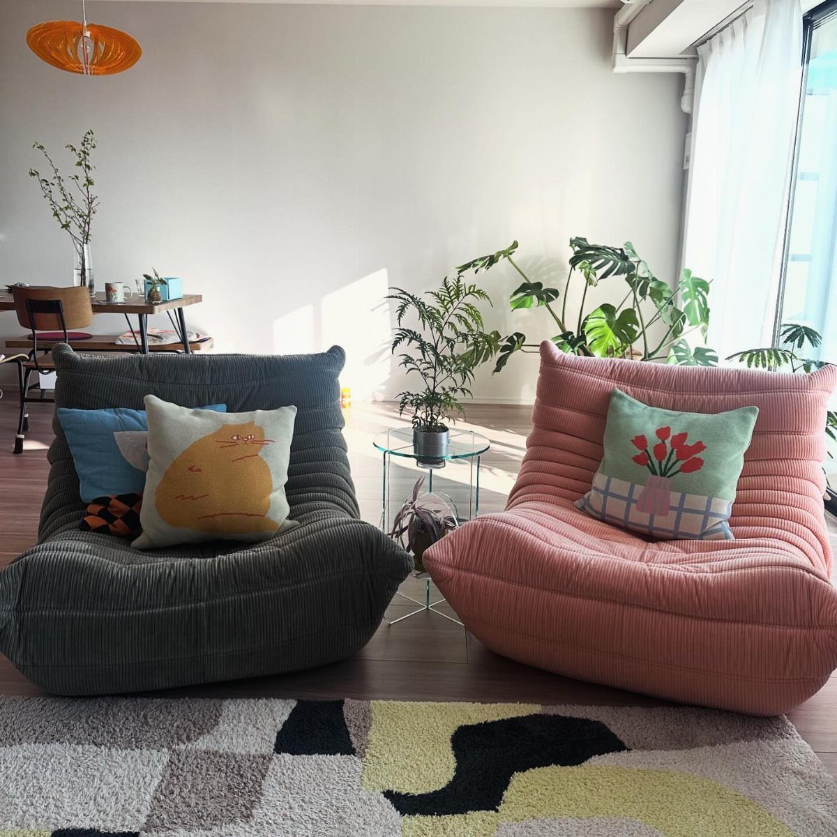 Grey and pink ribbed lounge chairs with colorful pillows in a bright living room