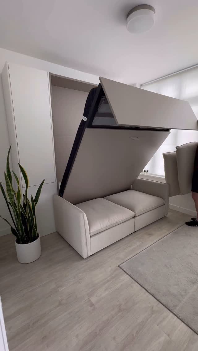 Beige folding wall bed partially open above a matching sofa in a small room