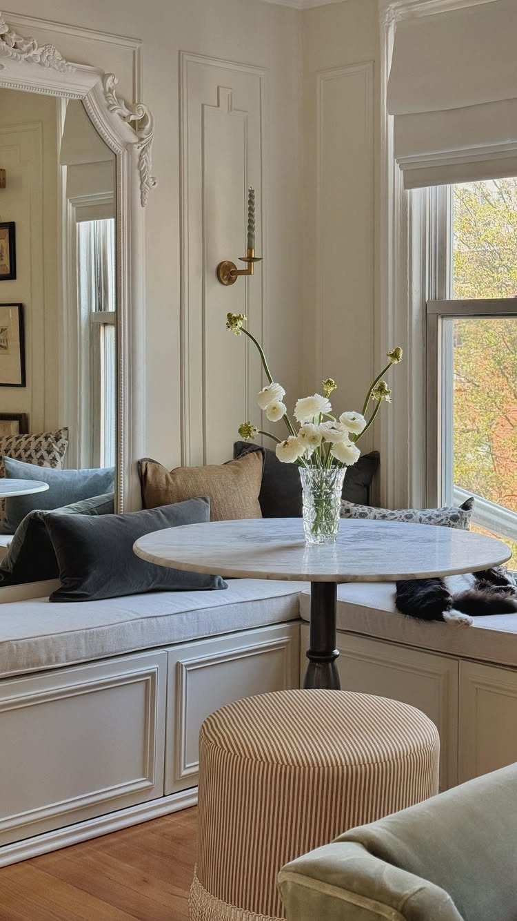 Built-in L-shaped banquette seating with a round marble table in a bright living room.