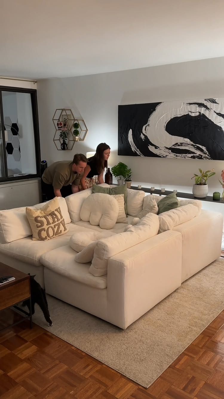White modular sectional sofa with cushions on a rug in a modern living room.