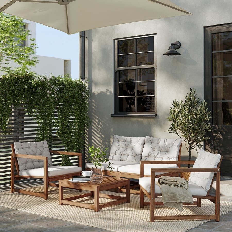 Wooden patio furniture set with grey cushions and coffee table on a rug.