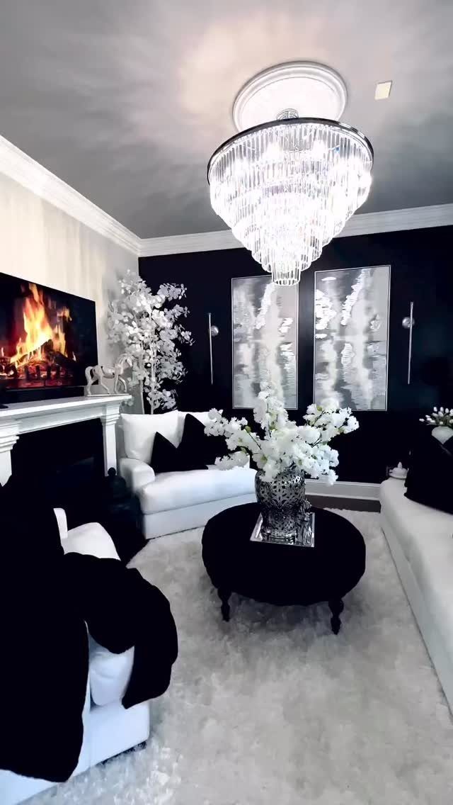 Living room with black accent wall, white sofas, and a large crystal chandelier.