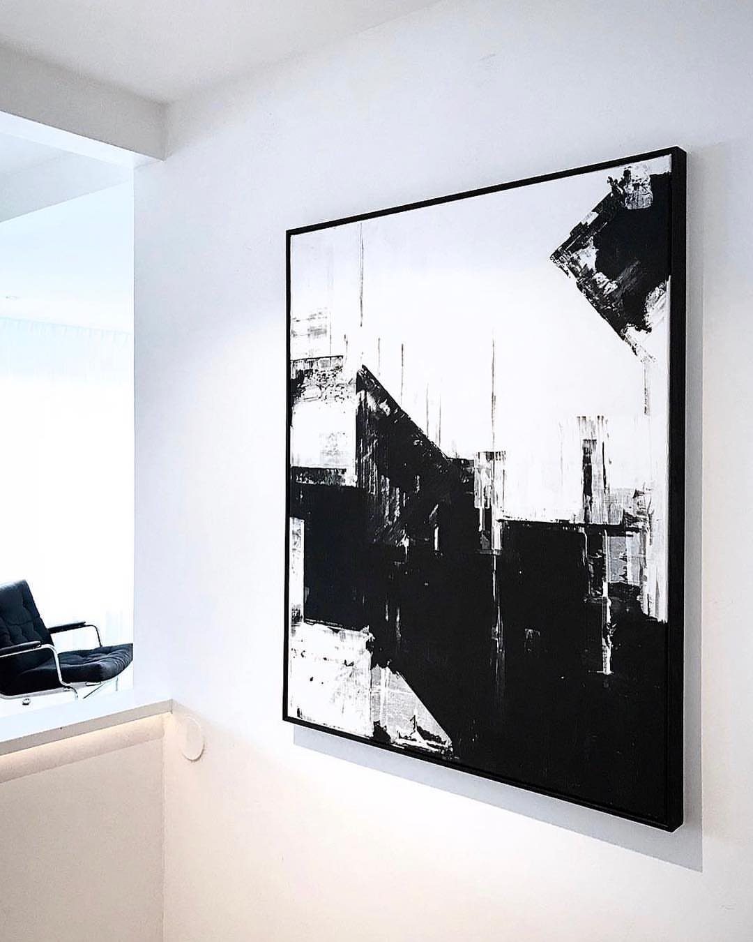 Large abstract black and white painting hanging on a clean white gallery wall