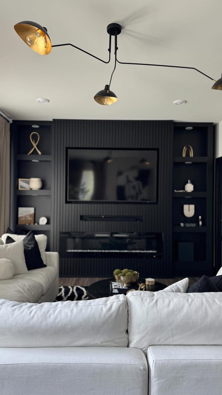 Modern living room with black fluted walls, white fabric sofas, and black lighting fixtures.