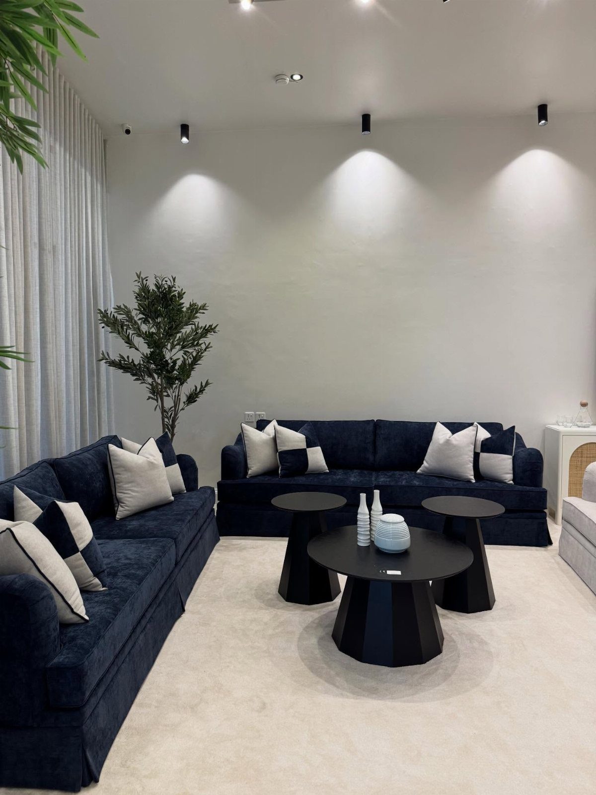 Navy blue velvet sofas with black and white pillows in a modern living room.