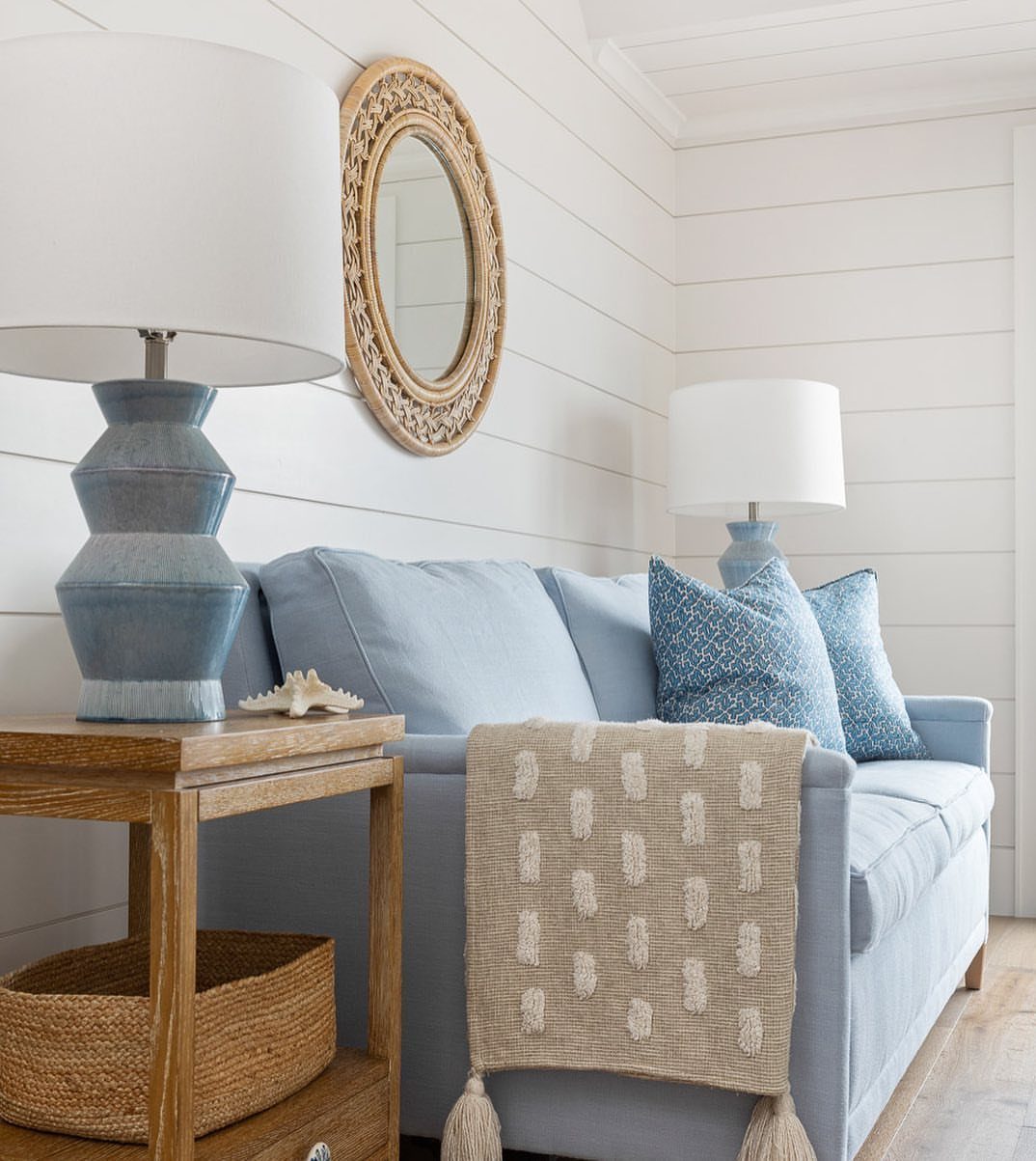 Light blue sofa with coastal decor, including a seashell and woven mirror accents.