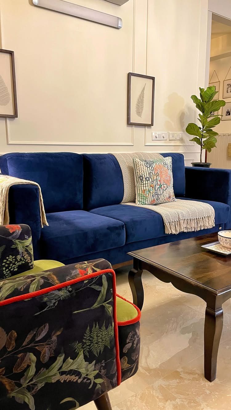 Blue velvet sofa with decorative pillows and a potted green plant in living room