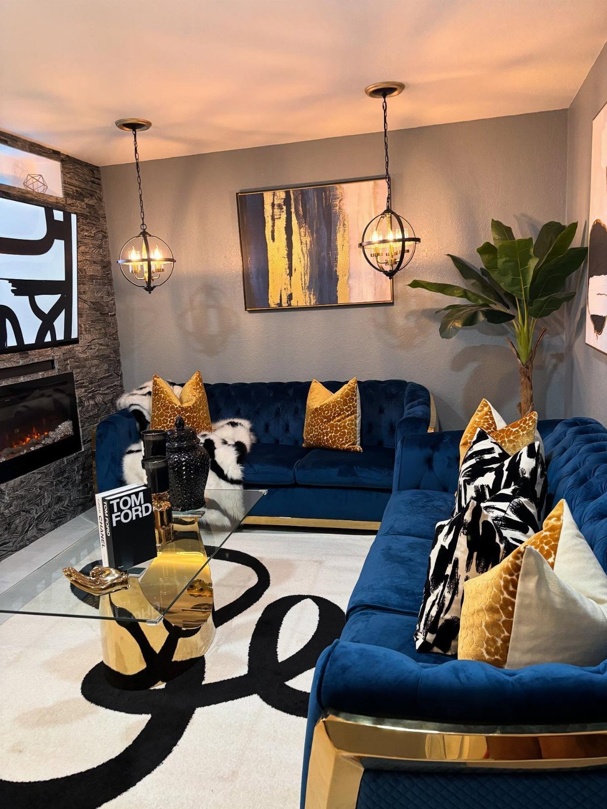 Navy blue velvet sofas with gold accents and patterned pillows in a modern living room.