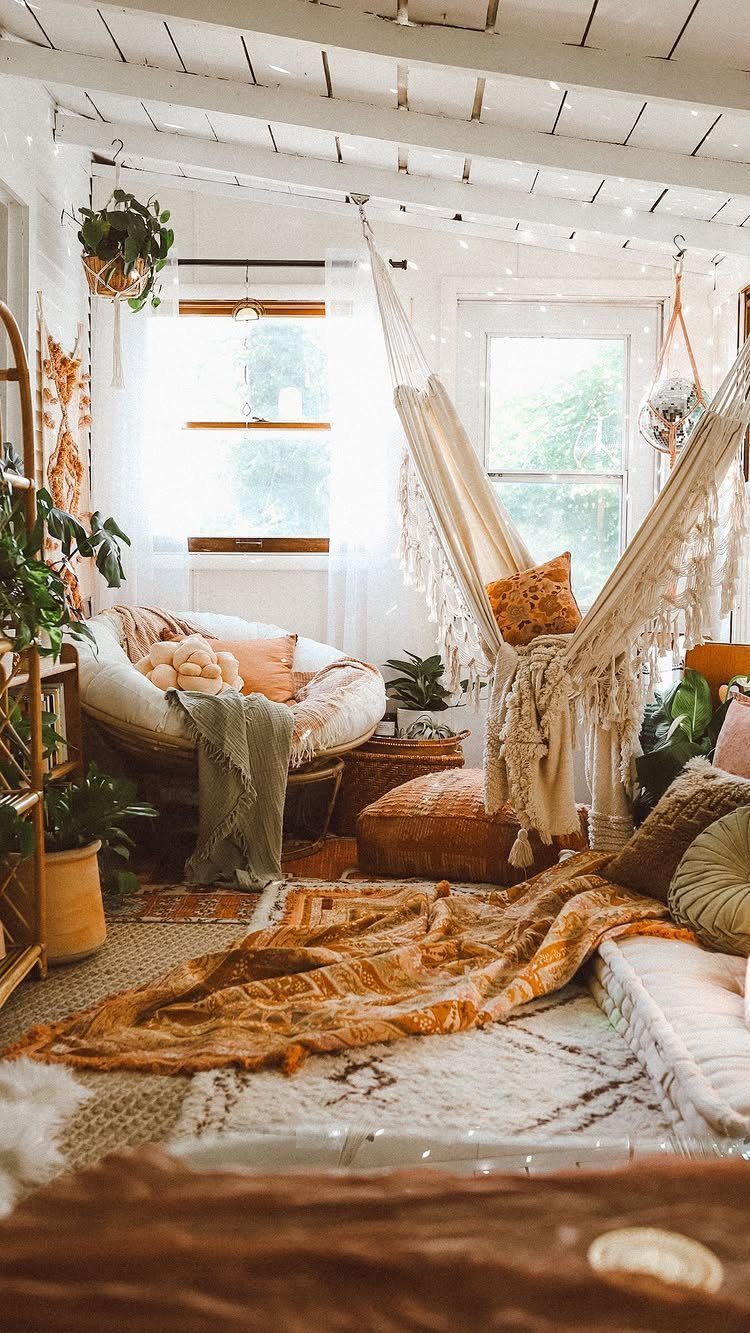 White macramé hammock chair and papasan chair in a boho room with plants.