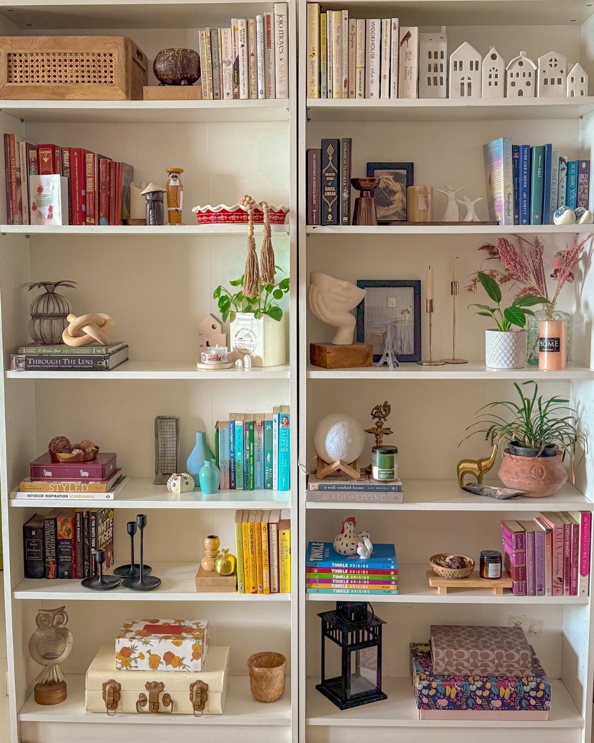 White bookshelves featuring a mix of vertical and horizontal book stacks with decor.