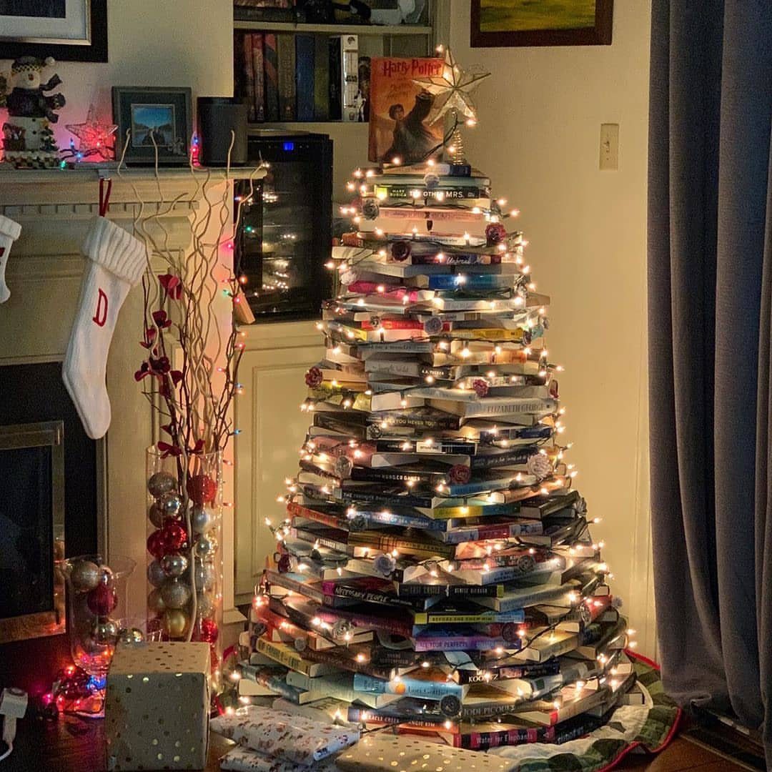 Book Christmas tree made of stacked books wrapped in glowing fairy lights.
