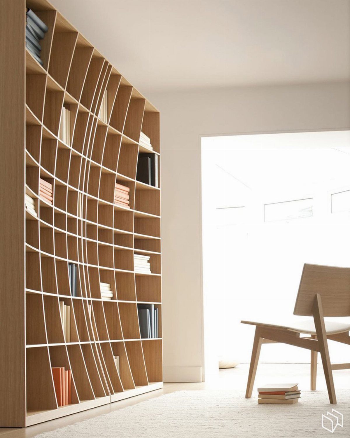 Curved light-wood built-in bookshelf in a bright white room with a wooden chair.