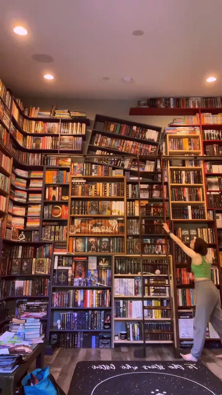 Floor-to-ceiling built-in bookshelves filled with books and a black rolling library ladder.