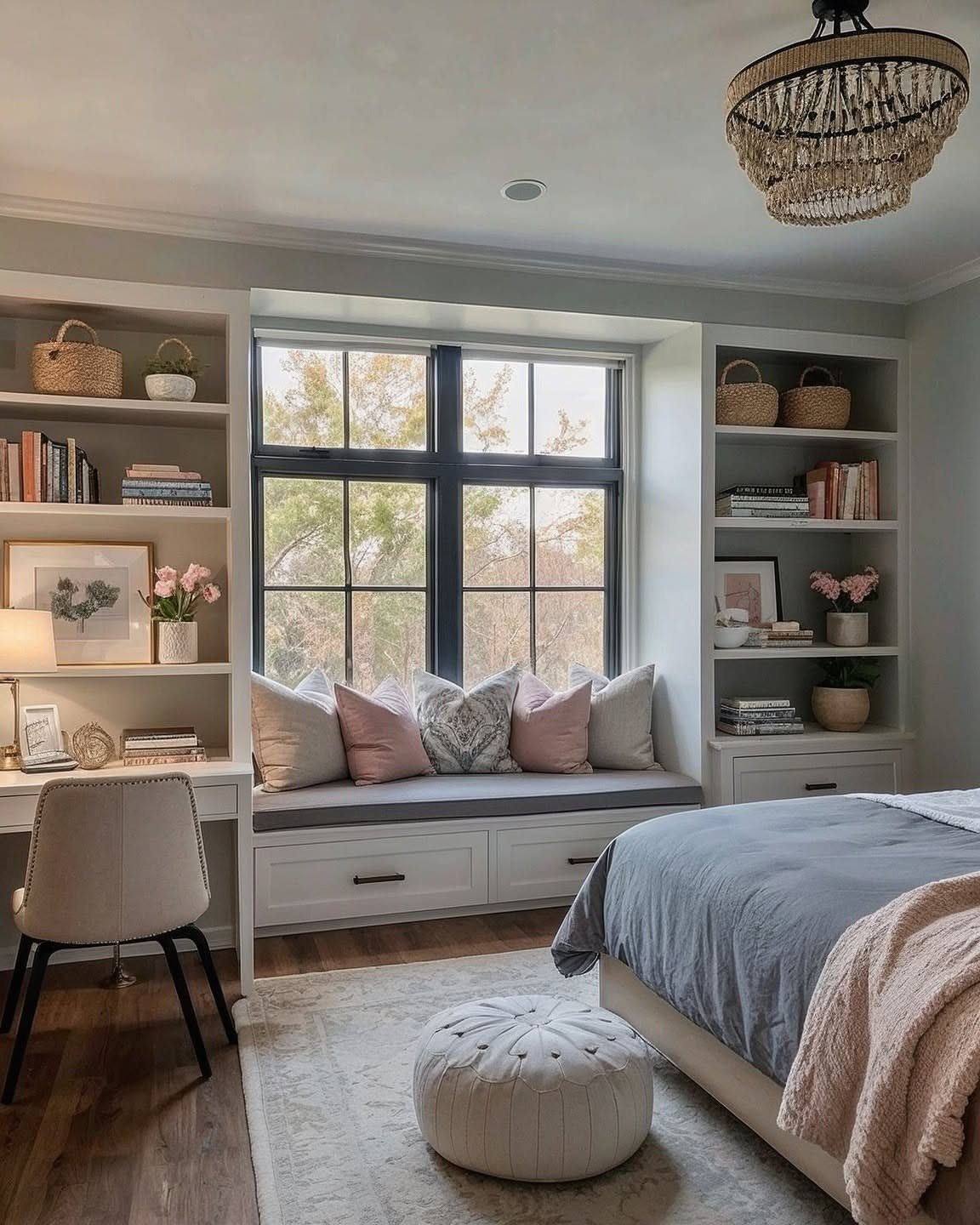 Built-in window seat with pink pillows between white bookshelves in a bright bedroom.