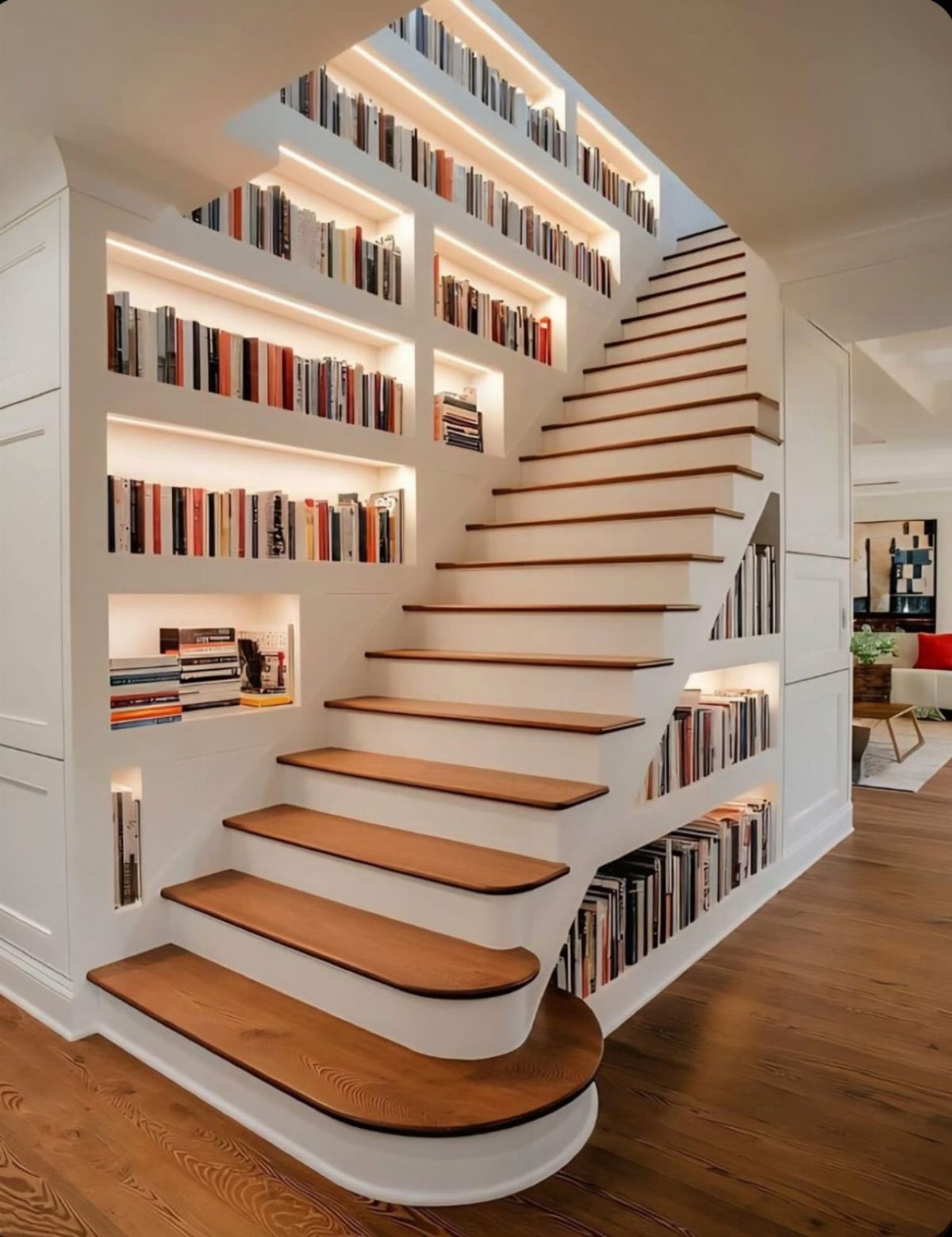 White built-in bookshelves integrated into a wall and under a curved wooden staircase.