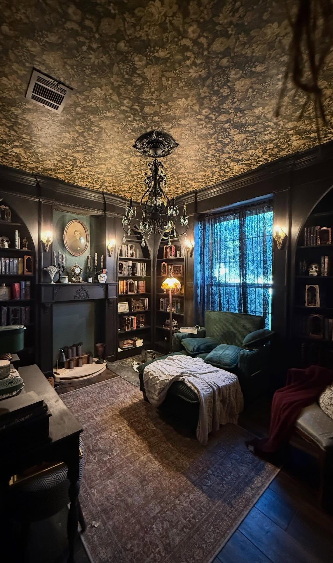 Dark ornate patterned wallpaper on a ceiling in a moody library living room