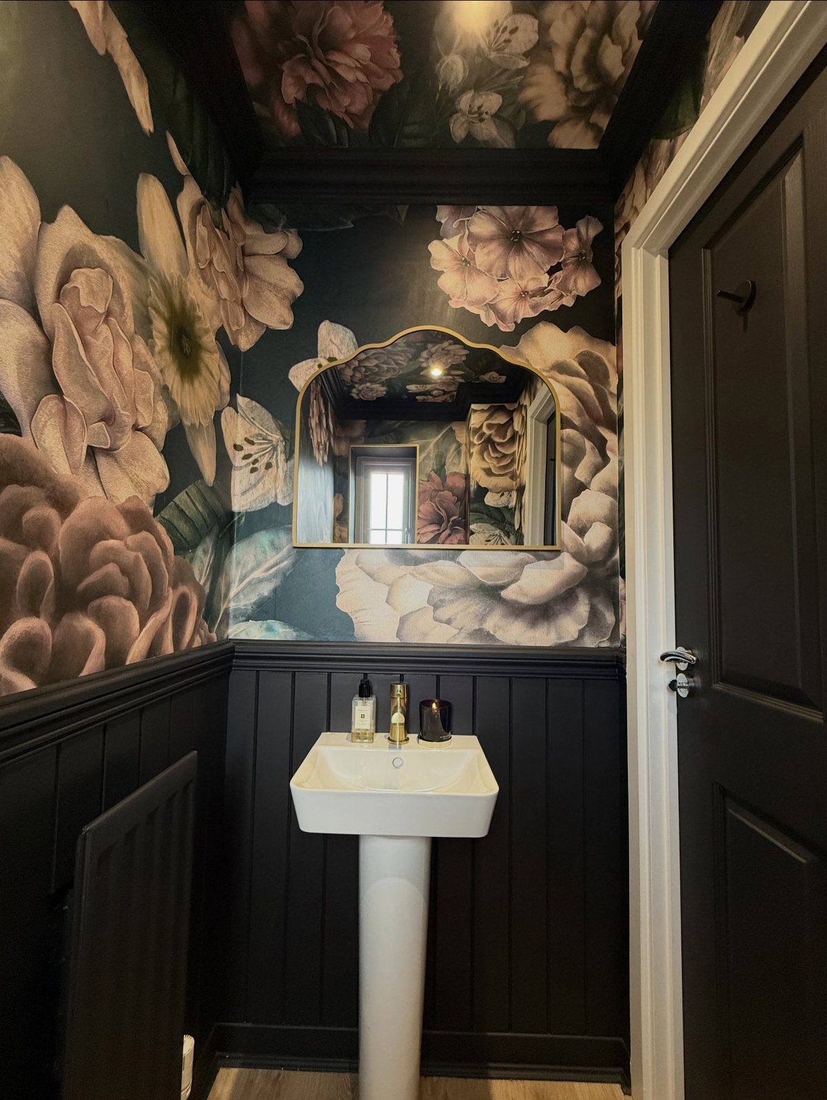 Bathroom with oversized floral wallpaper on the walls and ceiling above a white sink.