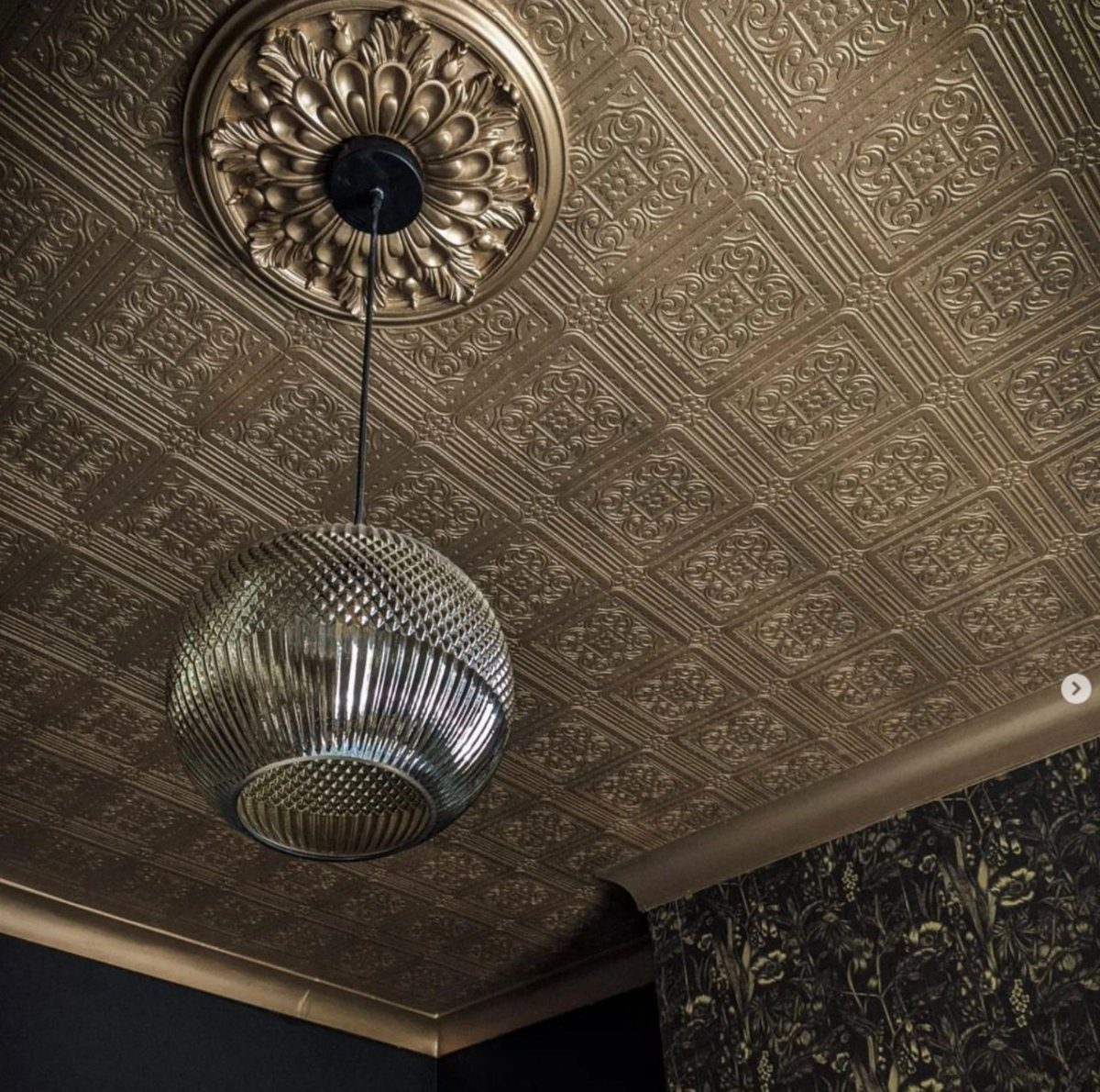 Gold metallic embossed ceiling with a decorative medallion and a ribbed glass pendant light.