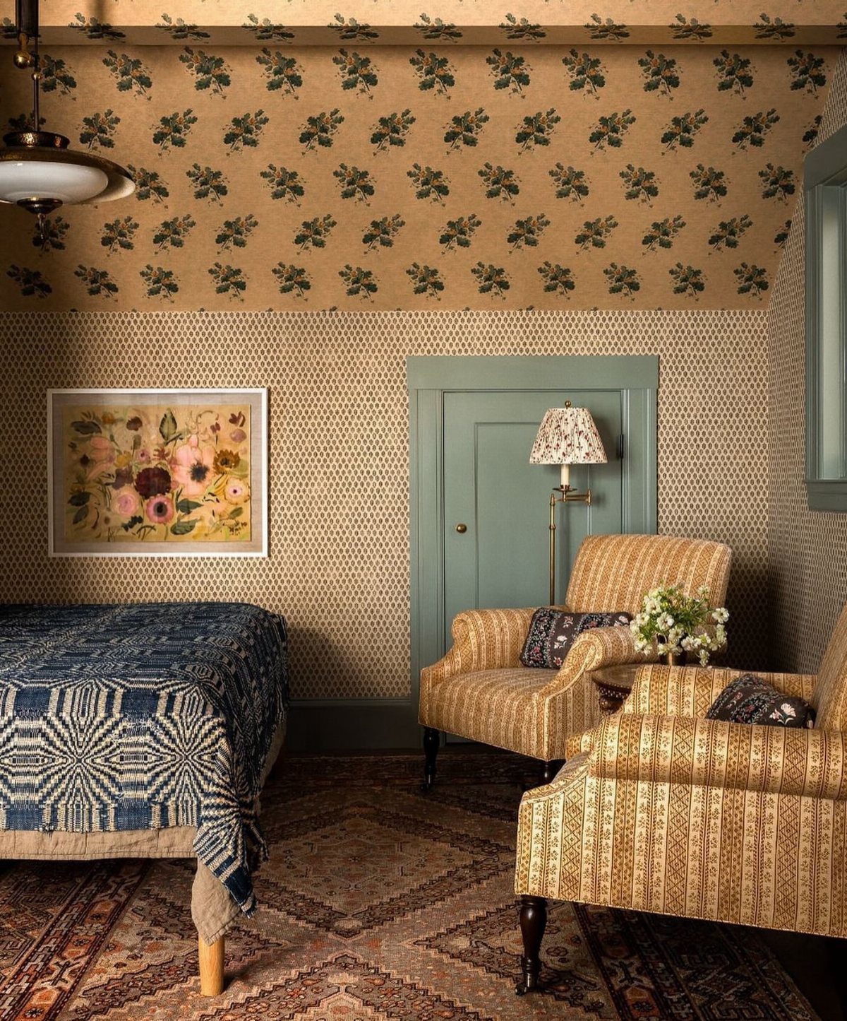 Sloped ceiling with tan and green leaf wallpaper in a cozy bedroom