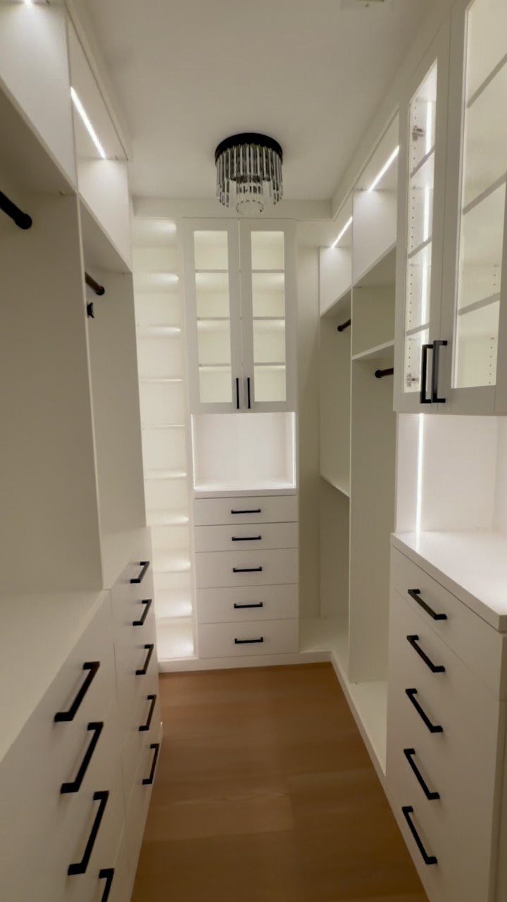 White walk-in closet with integrated LED strip lighting and a crystal ceiling chandelier.