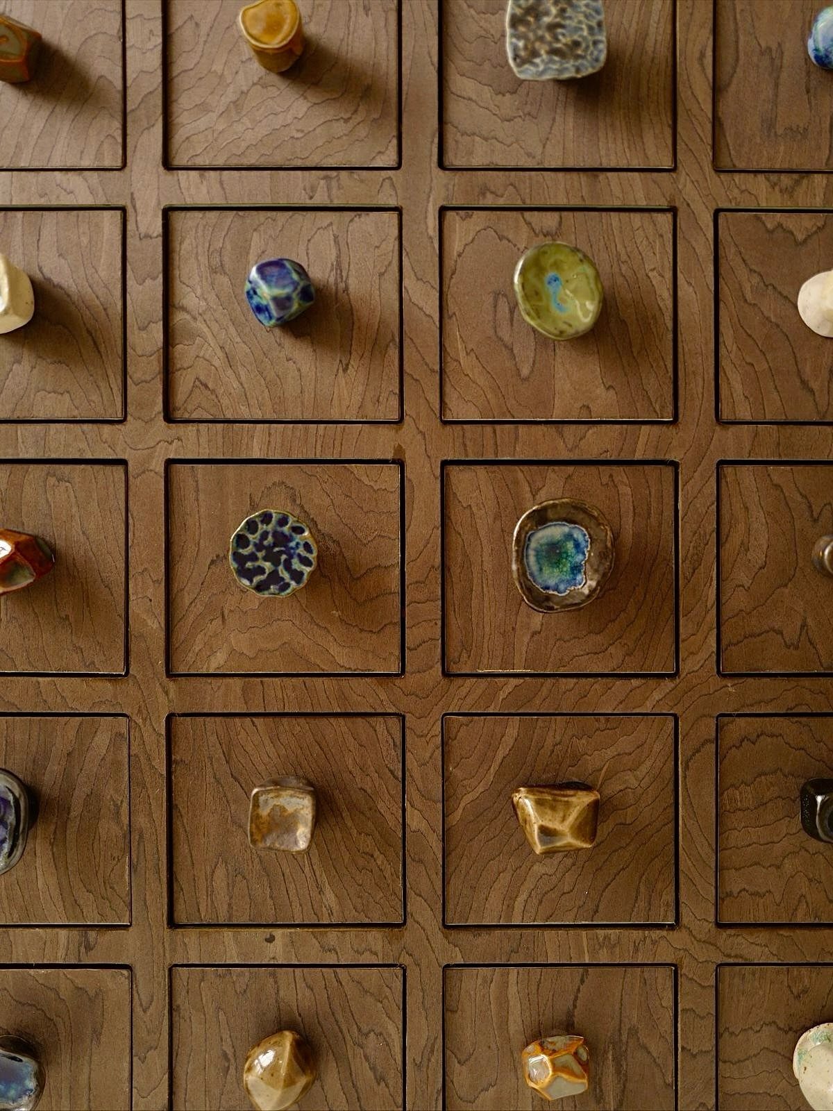 Wooden drawers with unique, colorful handcrafted ceramic knobs in various shapes and glazes.