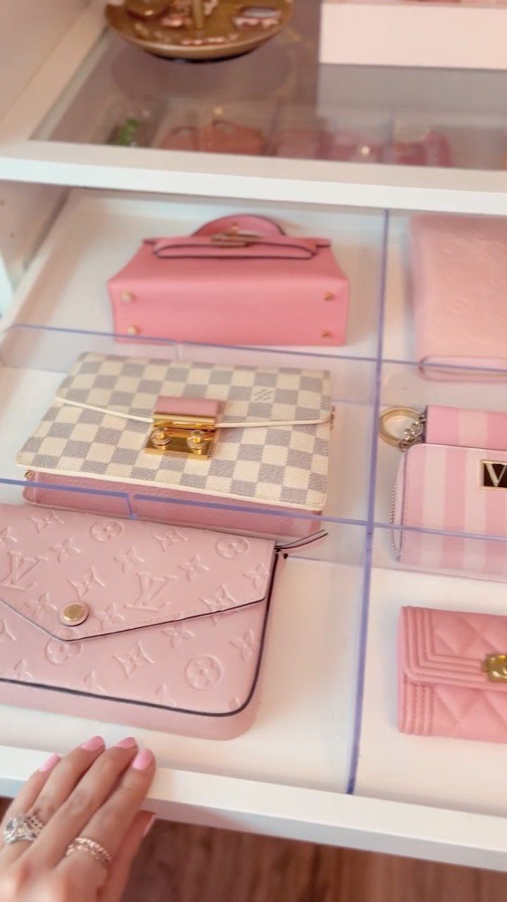 Luxury pink and beige handbags organized in a white drawer with acrylic dividers.