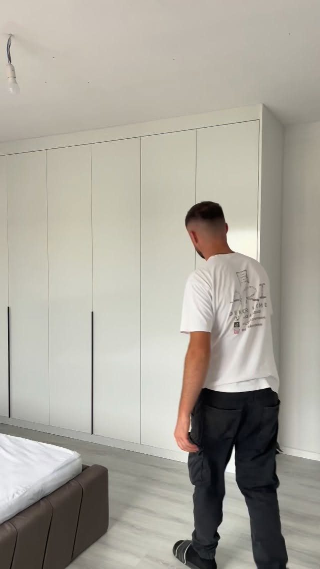 Man standing in front of a large white floor-to-ceiling built-in closet.