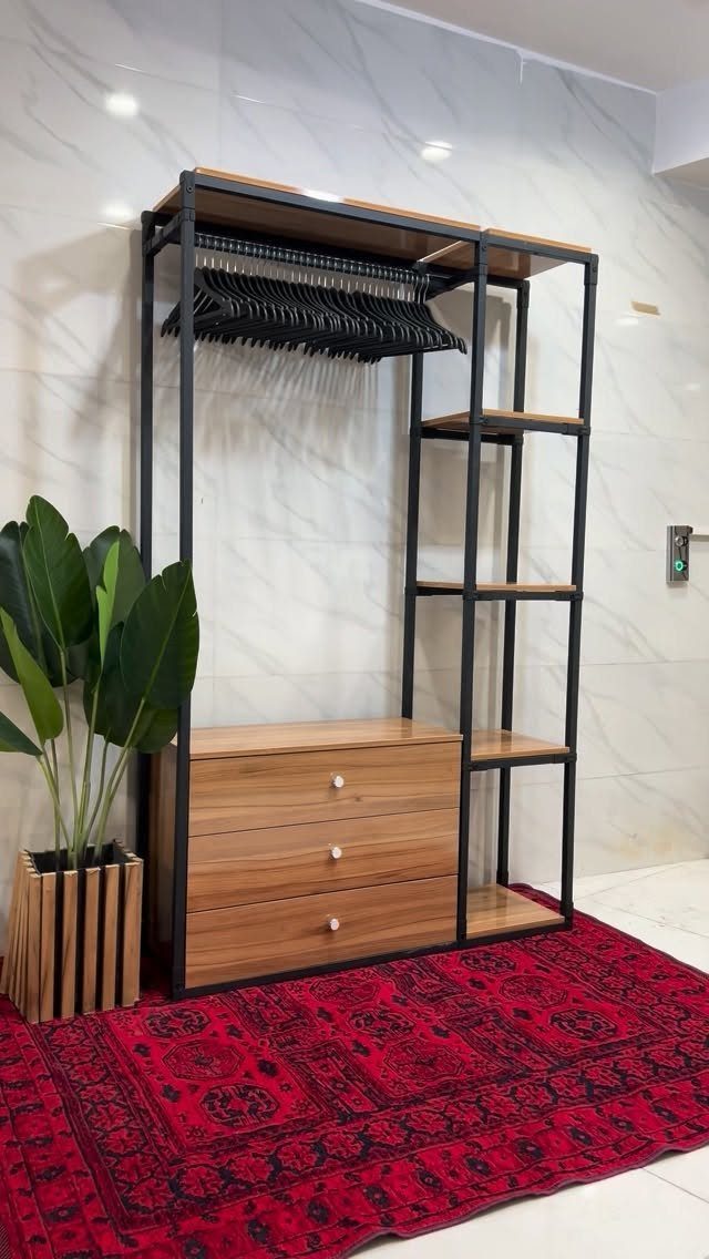 Black metal and wood open closet with hanging rod and drawers on red rug.
