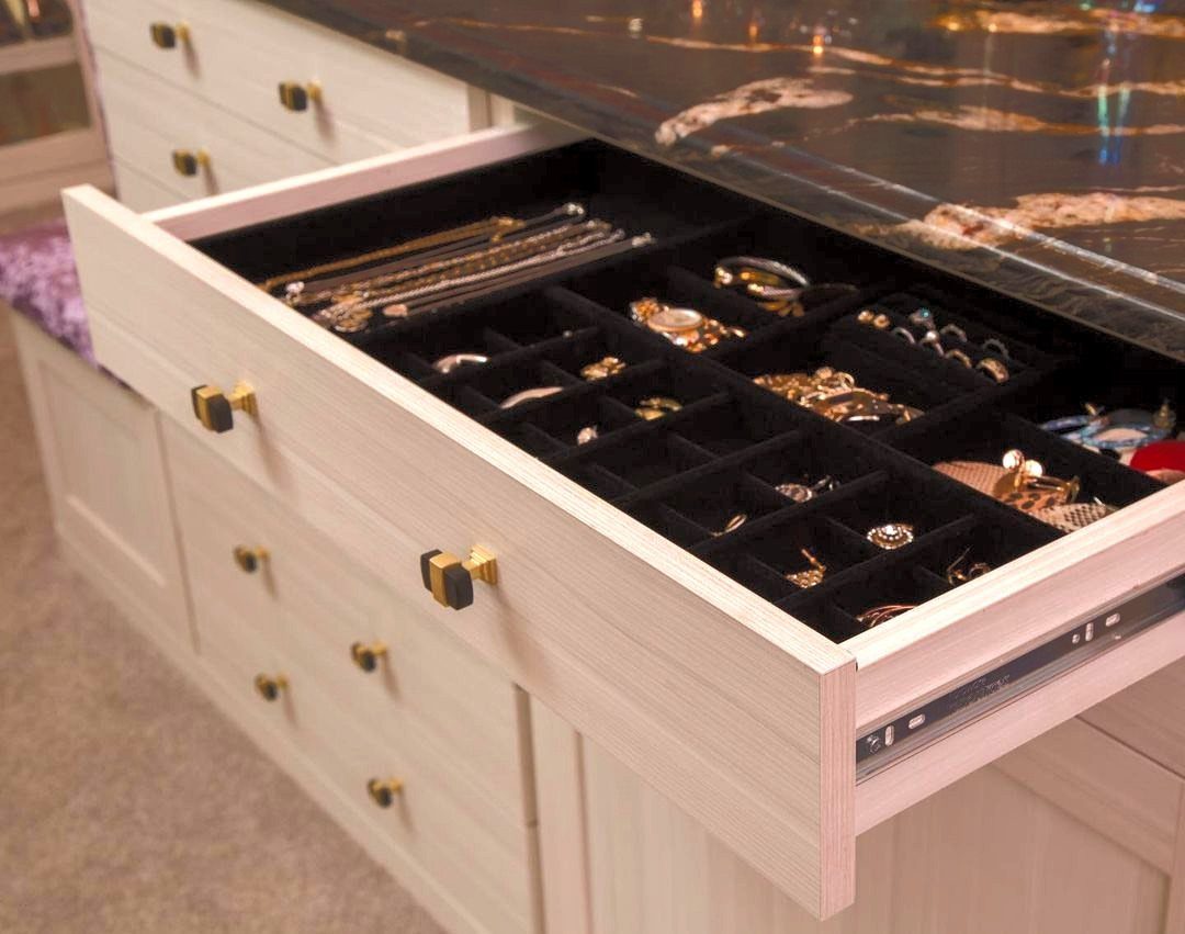 Black velvet-lined jewelry tray inside a white drawer containing gold rings and necklaces.
