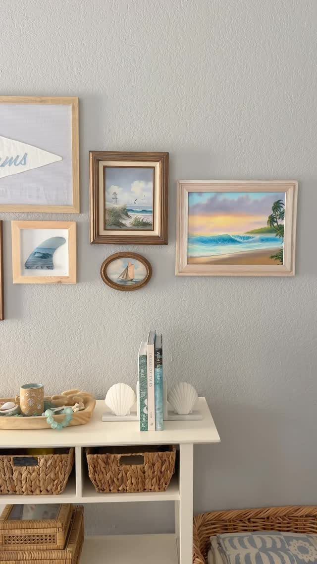Gallery wall of coastal art and a pennant above a white console table.