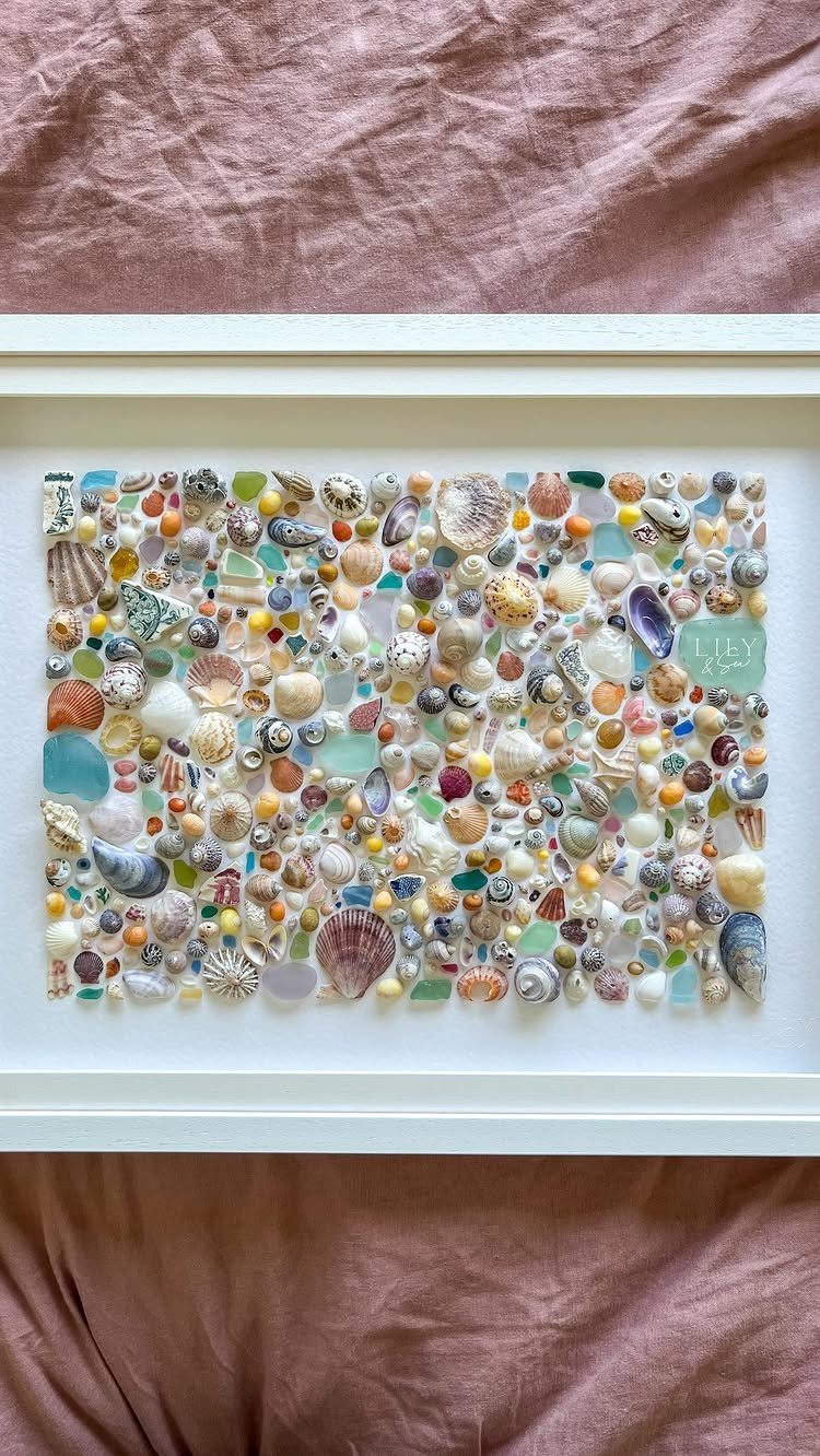 Framed mosaic art made of colorful sea glass and various small seashells.