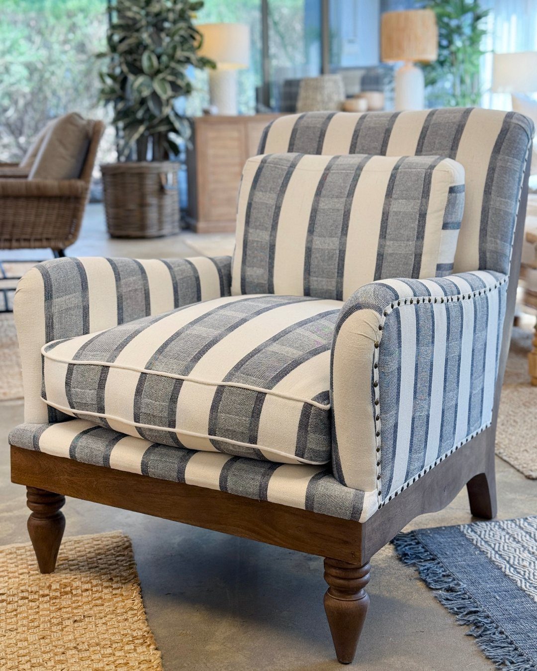 Blue and white striped accent chair with wooden legs in a coastal room