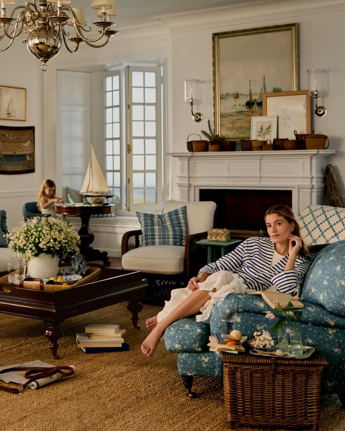 Coastal living room with blue sofa, white chairs, and jute rug near a fireplace.
