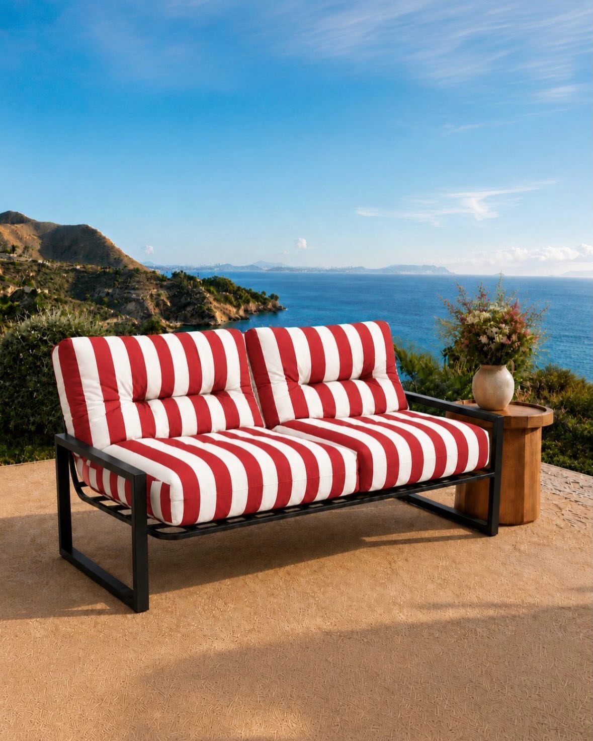 Red and white striped outdoor sofa on a patio overlooking the ocean coast.