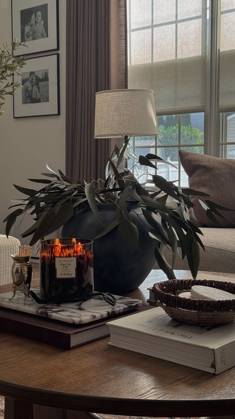 Lit black jar candle on a marble coaster atop a wooden coffee table.