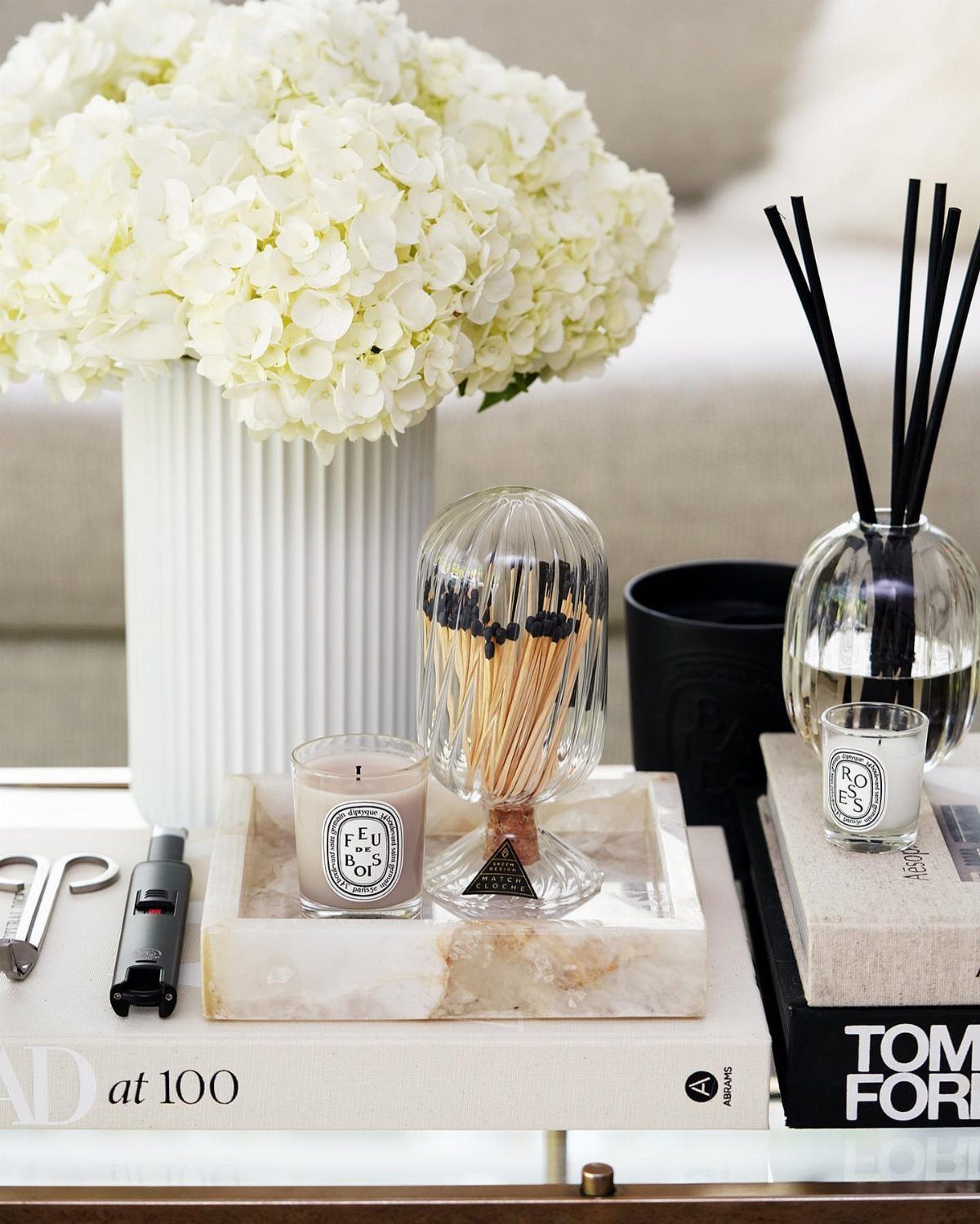 Glass cloche with matches and white flowers on a marble coffee table tray.