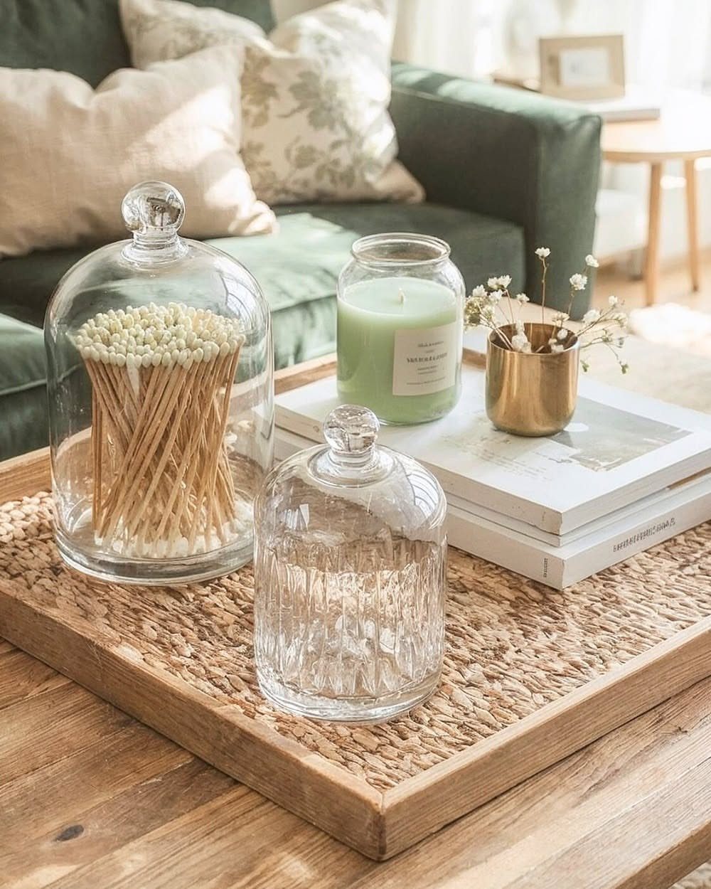 Wooden tray on a coffee table holding a candle, books, and glass cloches.