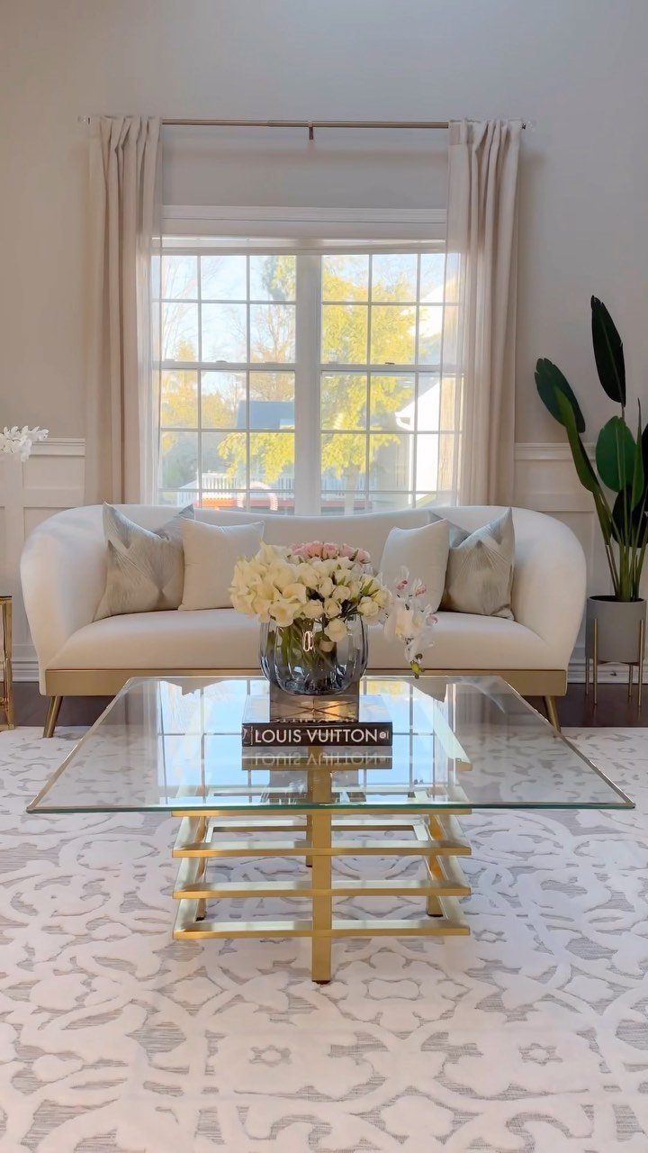 Low floral arrangement of white and pink flowers in a glass vase on a coffee table.