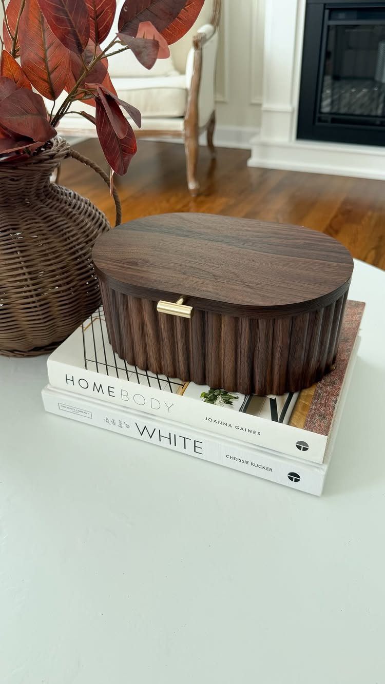Dark wood decorative box sitting on white coffee table books and a white surface