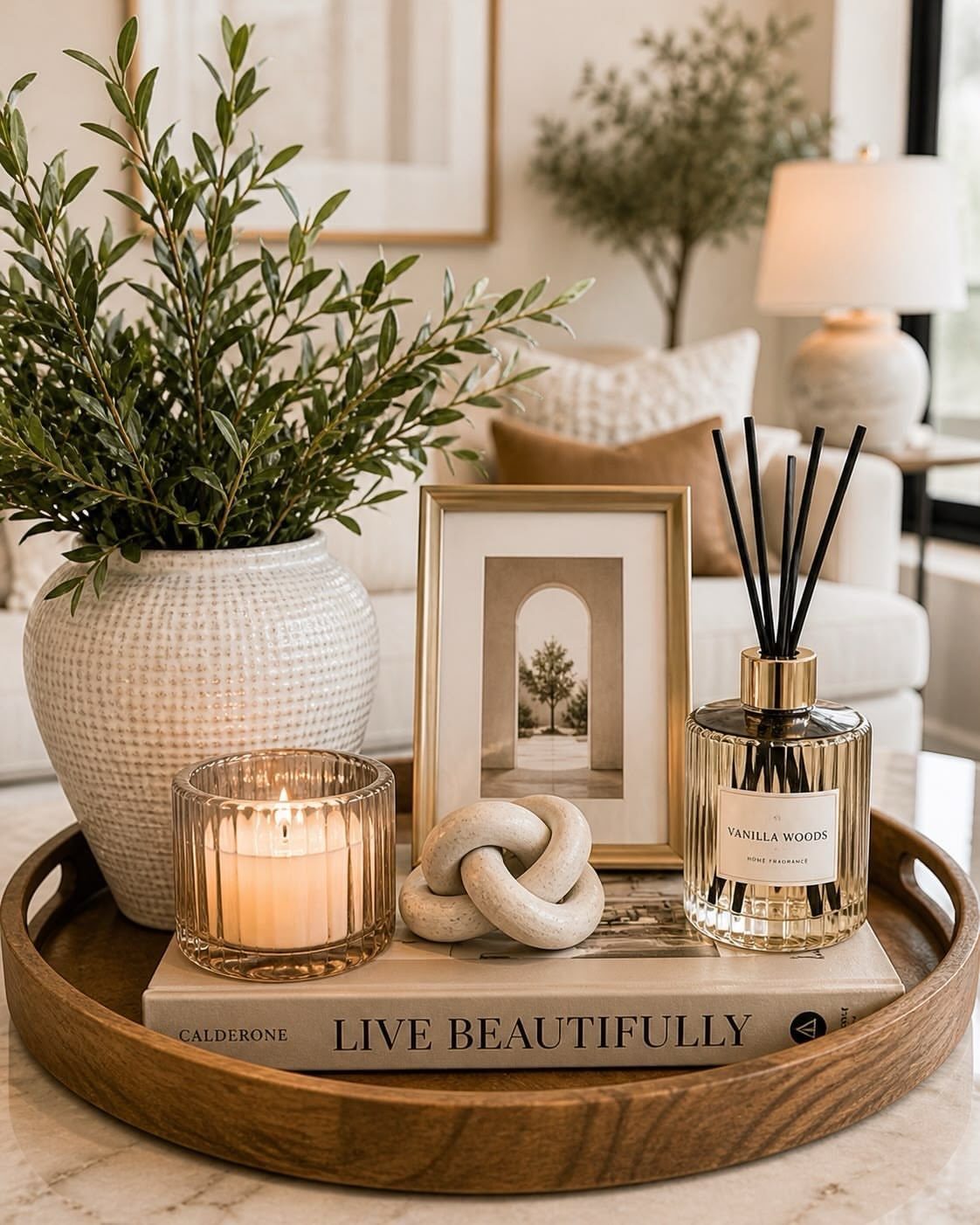 White textured vase with green leafy branches on a wooden coffee table tray.