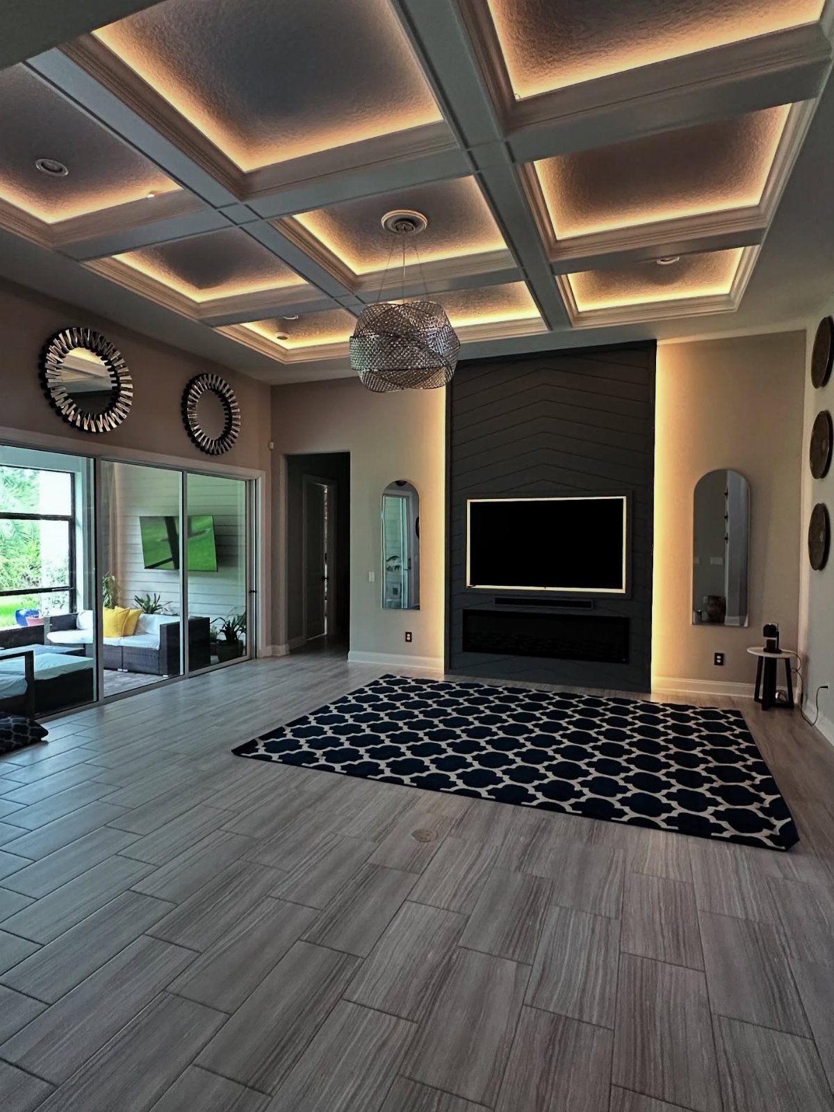 Modern living room with a coffered ceiling featuring integrated warm LED strip lighting.