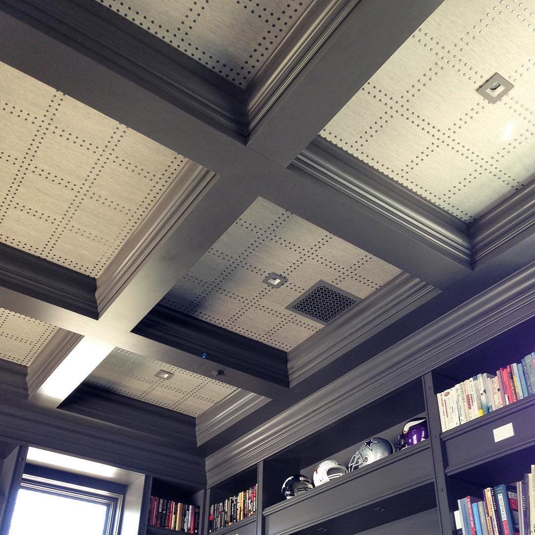 Dark grey coffered ceiling with dotted wallpaper panels above built-in bookshelves.