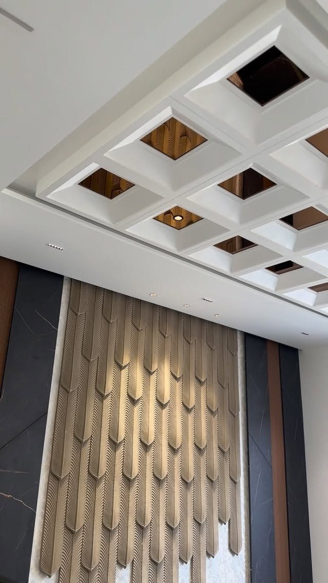 White coffered ceiling with wooden inserts above a textured gold geometric wall.