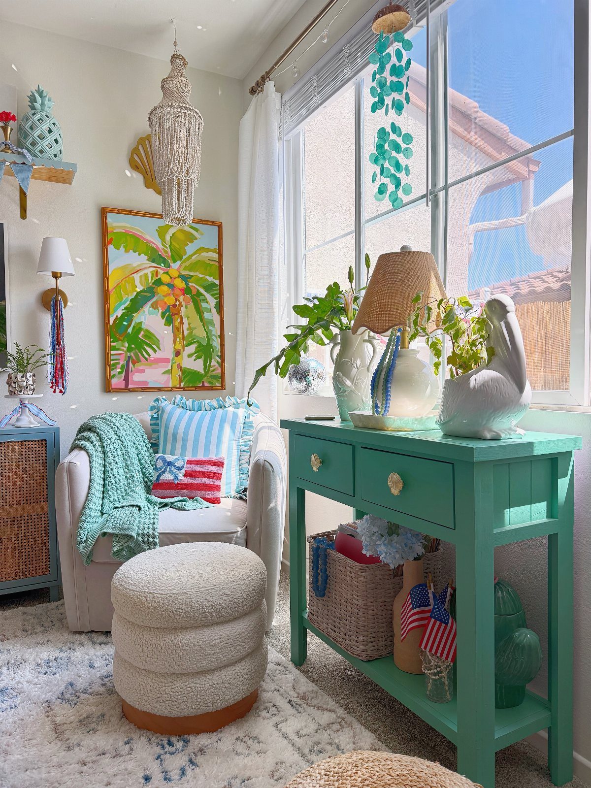 Bright room with teal furniture, palm tree art, and blue and white textiles.