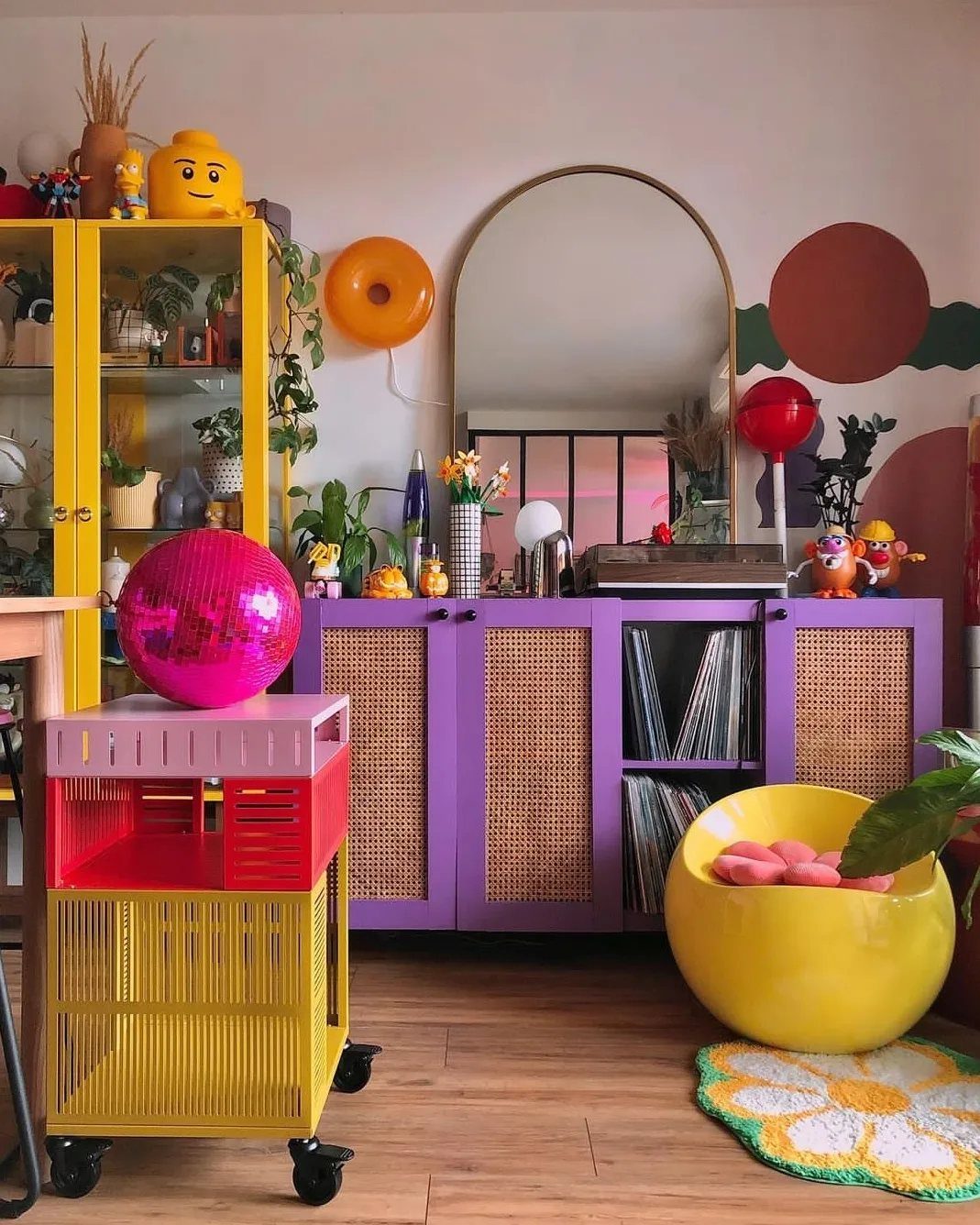 Vibrant room with purple sideboard, yellow furniture, and a pink disco ball.