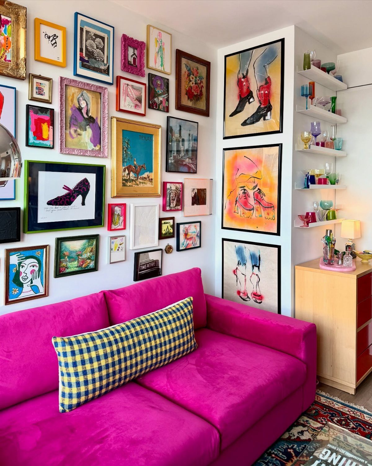 Pink sofa in a room with a gallery wall of colorful framed art.