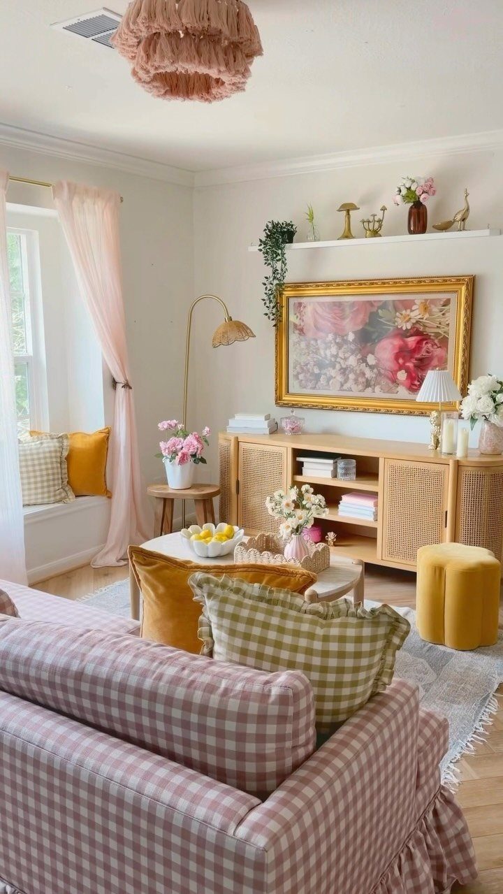 Colorful living room corner with pink checkered sofa, yellow furniture, and floral artwork.