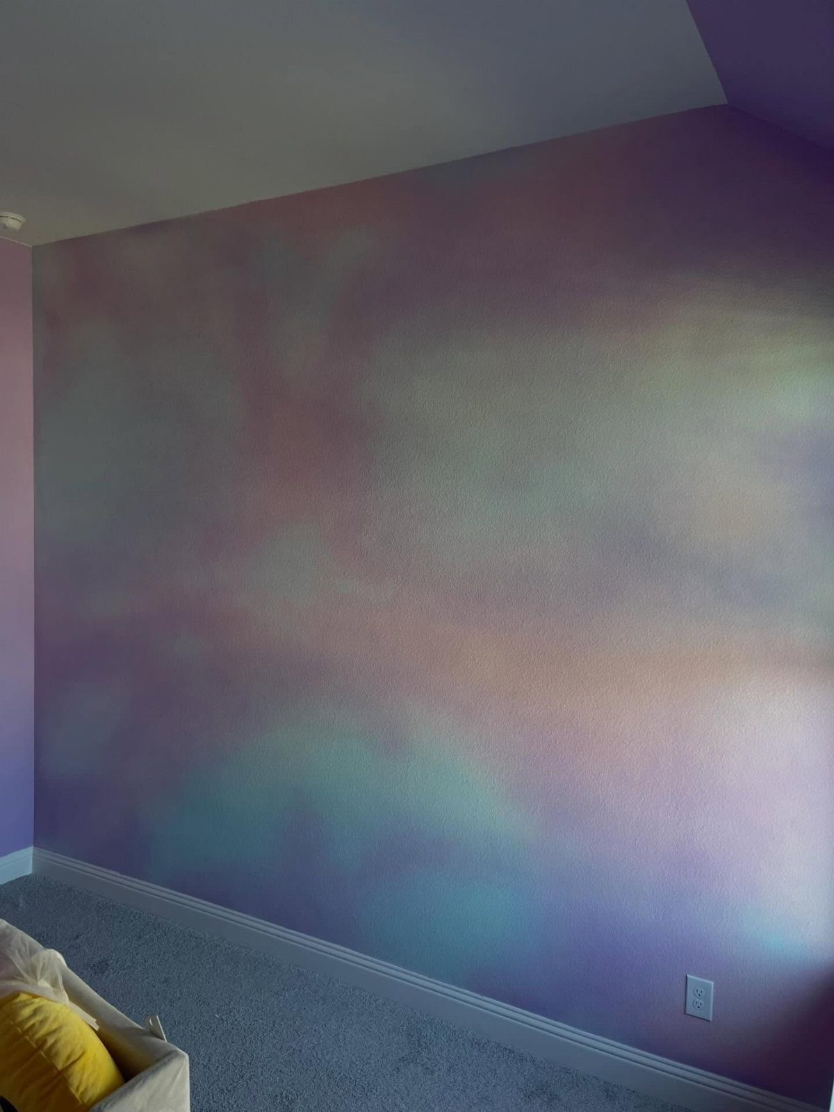 Wall with blended purple, blue, and pink paint in a cloud-like pattern.