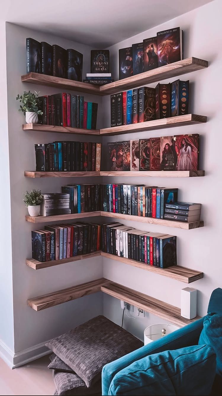 L-shaped wooden floating shelves in a corner filled with books and small plants.